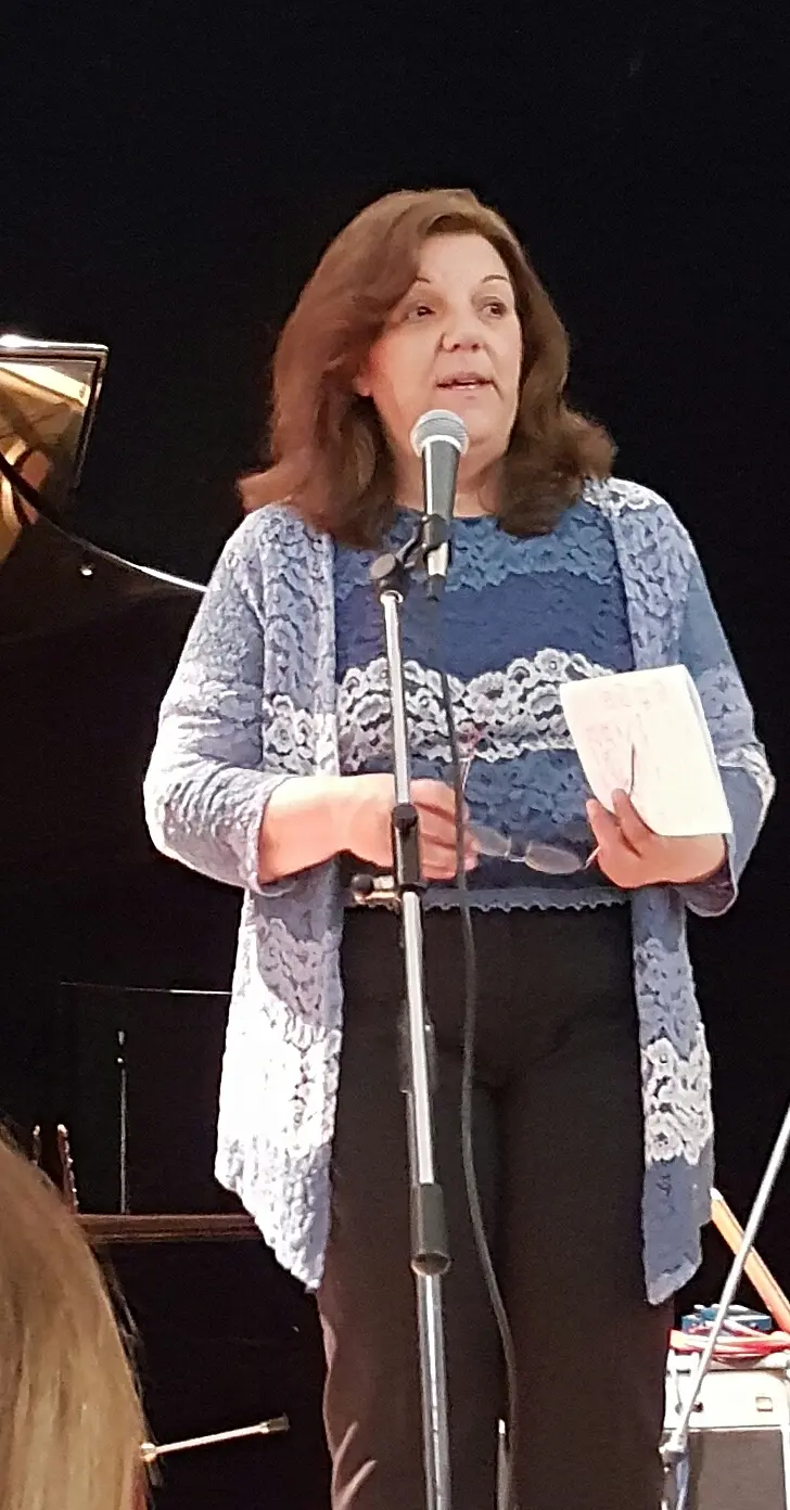 Daniela Donaudi durante una presentazione pubblica, ritratta a figura intera accanto al pianoforte